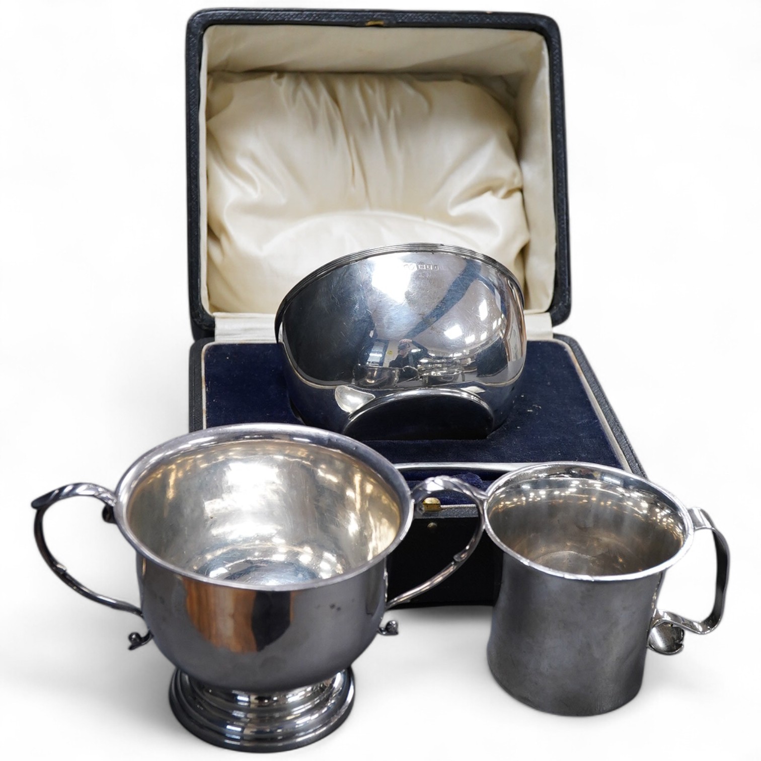 A George V Britannia standard silver mug, by Thomas Bradbury & Sons, Sheffield 1918, height 65mm, handle a.f., together with a 1930's silver porringer and a George V cased silver christening bowl and spoon, 13.2OZ.